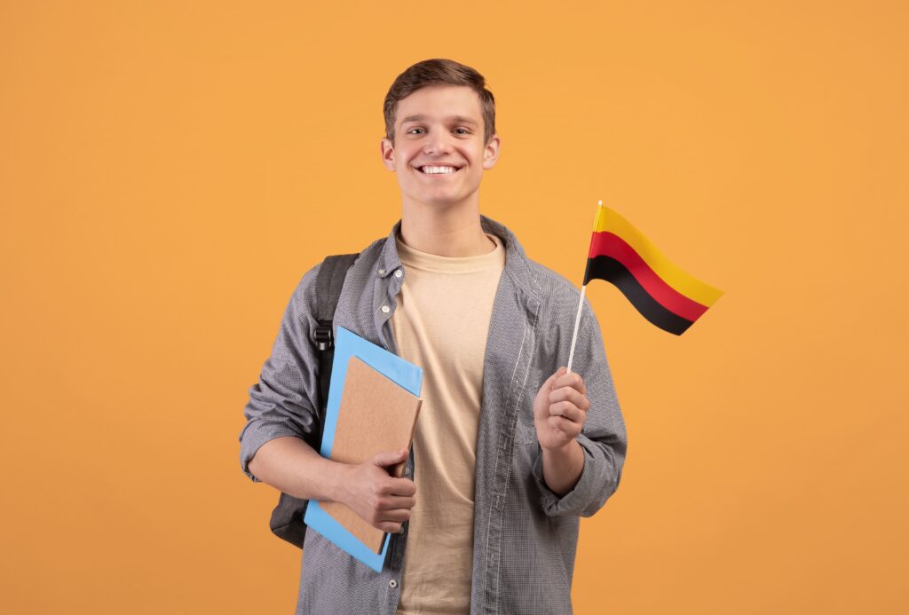 Étudiant souriant tenant un drapeau allemand et des cahiers